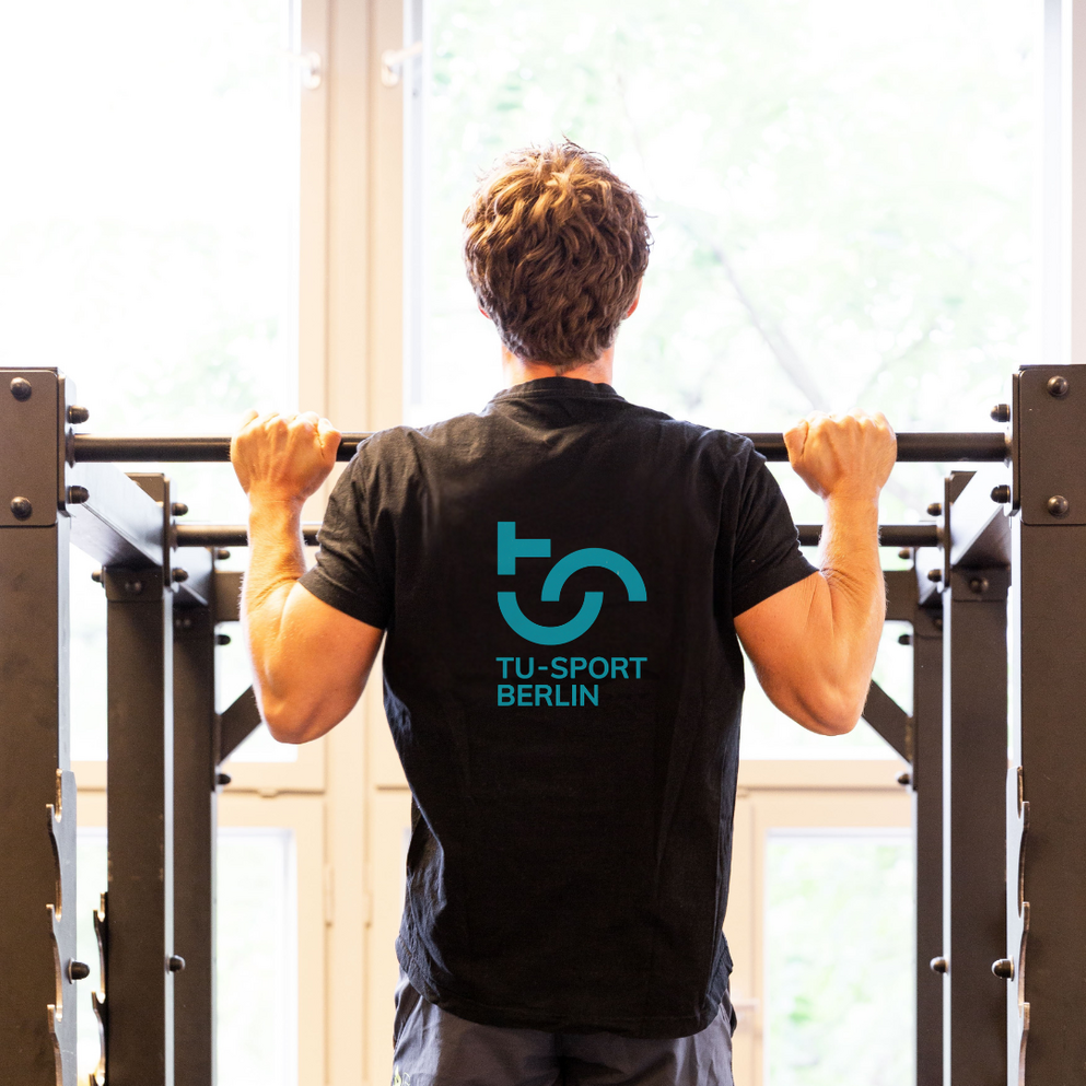 Mann, der einen Klimmzug macht mit TU-Sport-Logo auf dem Rücken