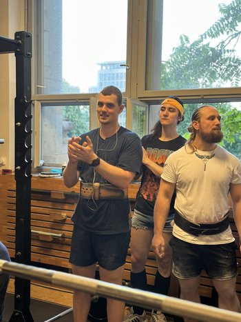 Drei Männer in Sportkleidung und einer klatscht in die Hände.