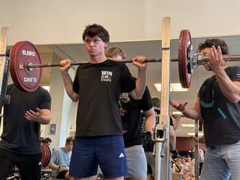 Ein Mann in schwarzem Shirt macht eine Kniebeuge.