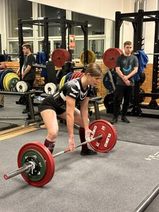 Frau im TU-Fitness-Studio, die Kreuzheben mit viel Gewicht macht