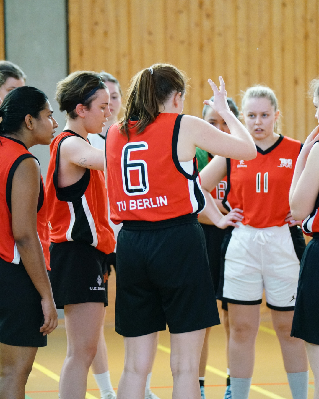 Frauen-Basketballteam in TU-roten Trikots berät sich in einer Runde